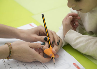 Terapeuta Ocupacional ayudando a un niño con el lápiz